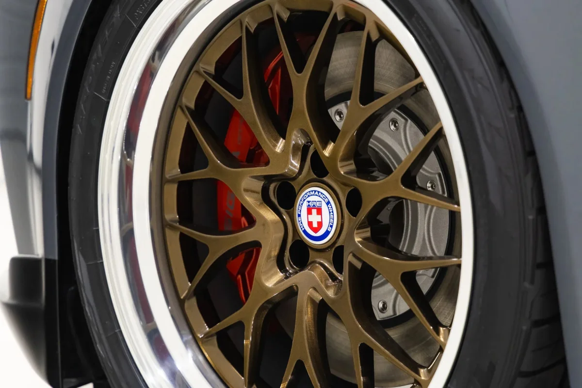 Bronze HRE multi-spoke wheel with a polished lip, featuring a red brake caliper visible behind the spokes.