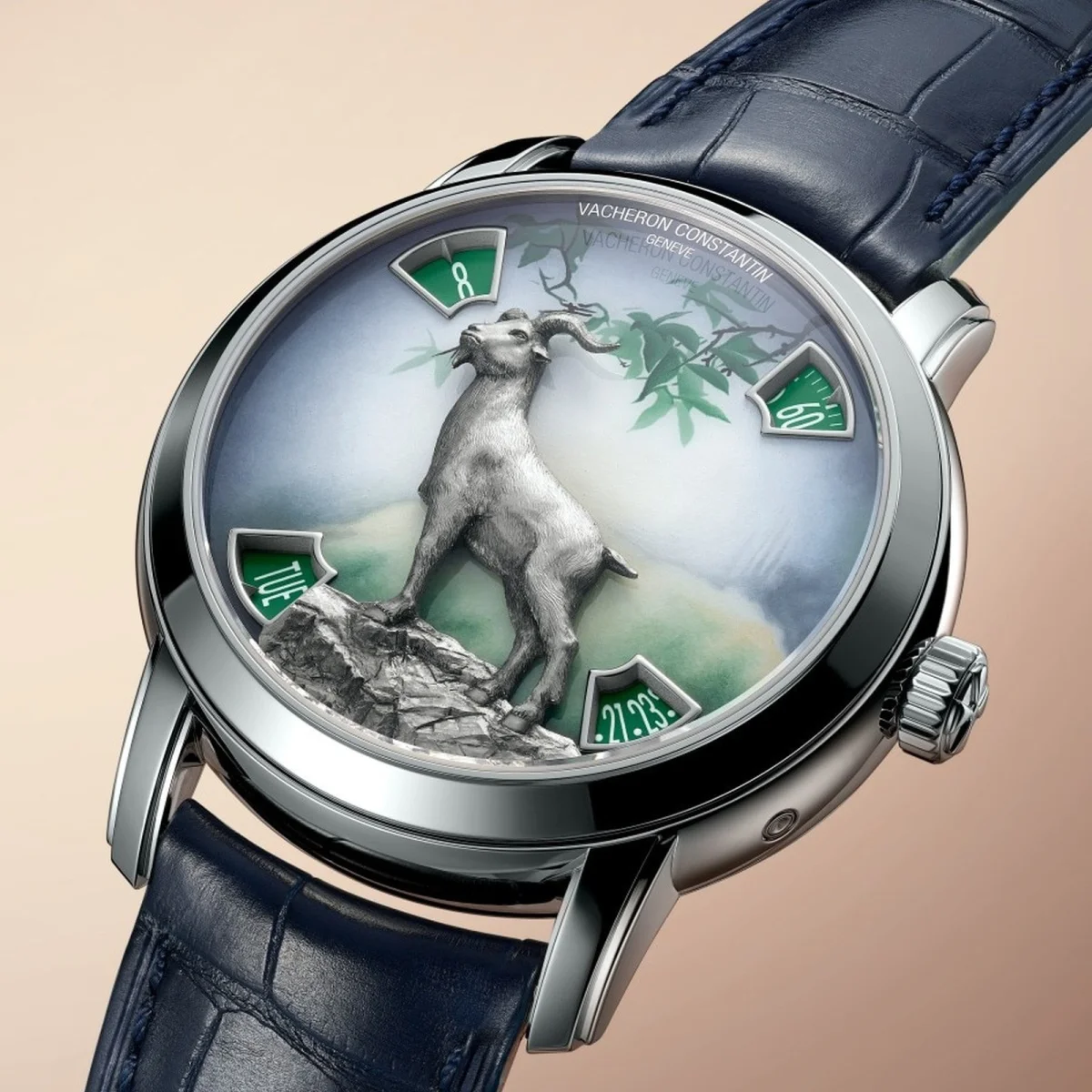 Vacheron Constantin watch featuring a silver goat sculpture on a painted dial with four green apertures for time and date, with a dark blue leather strap.