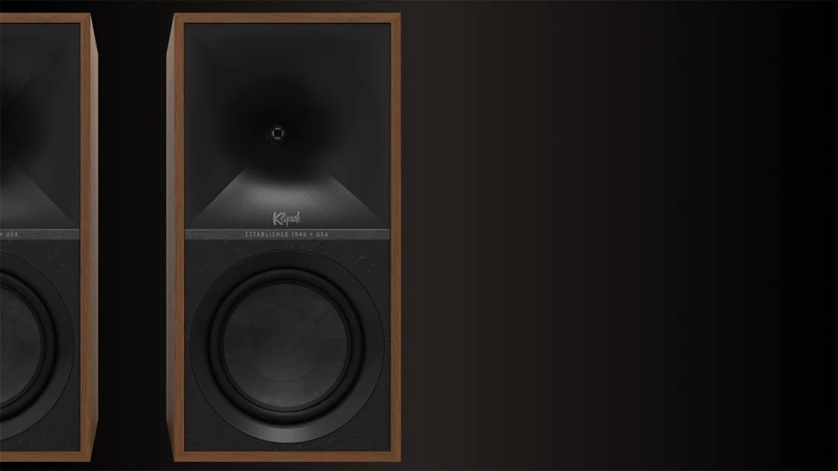 Pair of Klipsch speakers with wooden frames and black front panels on a dark background.