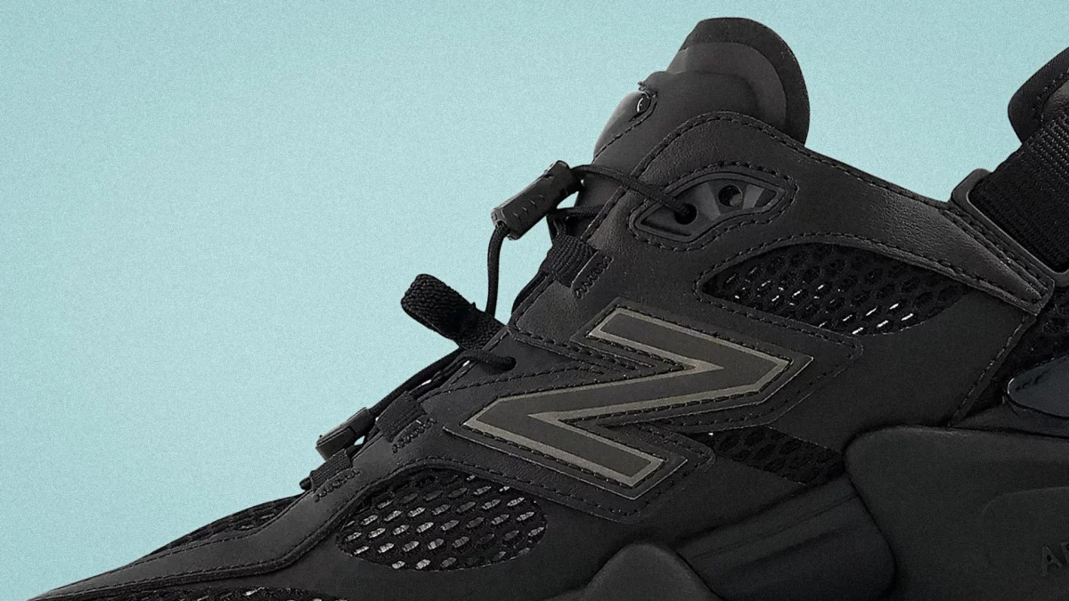 Close-up of a black New Balance sneaker with mesh panels and reflective details.