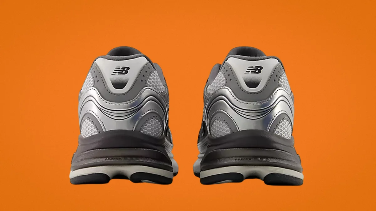 Pair of silver and gray New Balance running shoes shown from the back on an orange background.