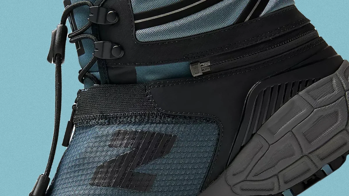Close-up of a blue and black sneaker with black laces and a textured gray sole.