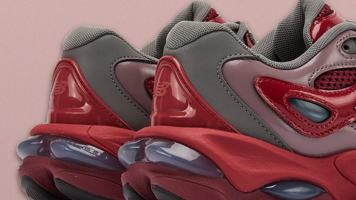 Two chunky sneakers shown from the back and side, featuring red, gray, and maroon accents with glossy overlays, mesh fabric uppers, and translucent rounded soles on a pale pink background.