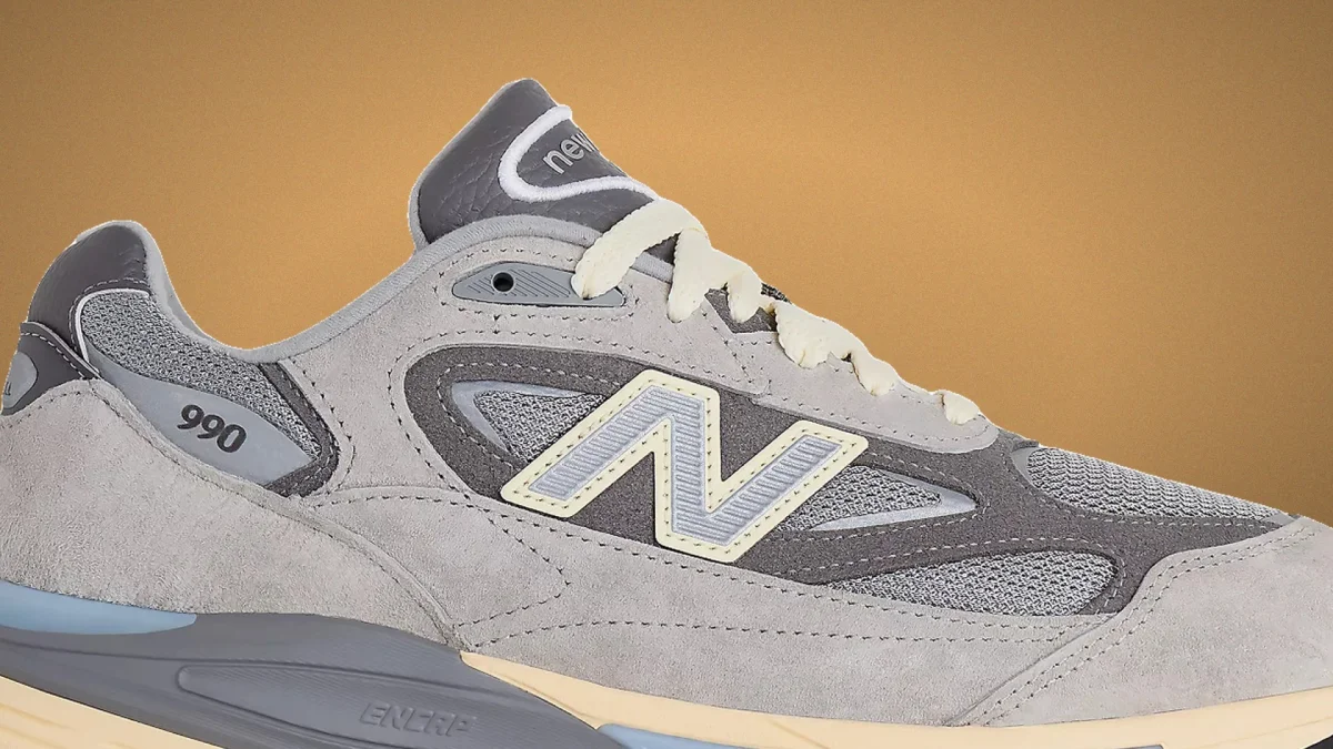 New Balance 990 running shoe in grey and charcoal featuring a cream-colored N logo, matching laces, and a two-tone foam midsole.