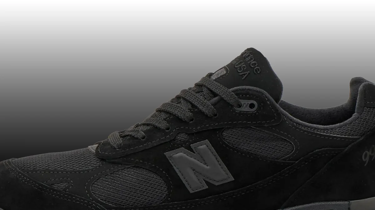 Close-up of a black New Balance sneaker with mesh and suede panels.