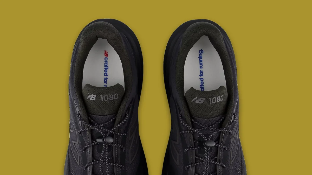 Black New Balance 1080 running shoes viewed from above on an olive green background, with crafted for running text visible on the insoles.