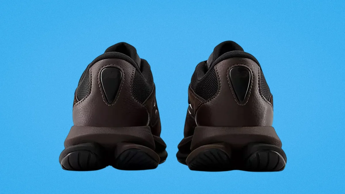 Pair of dark brown and black athletic shoes shown from the back on a blue background.
