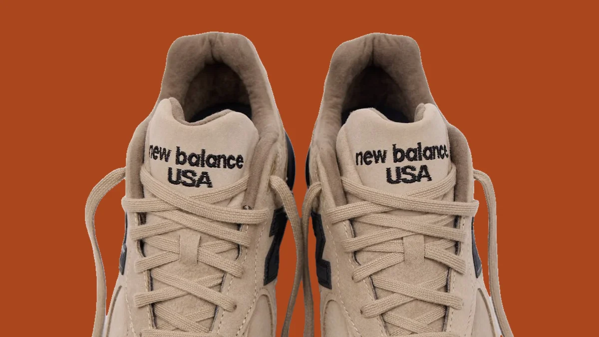 Tan New Balance USA sneakers with black branding on the tongues.