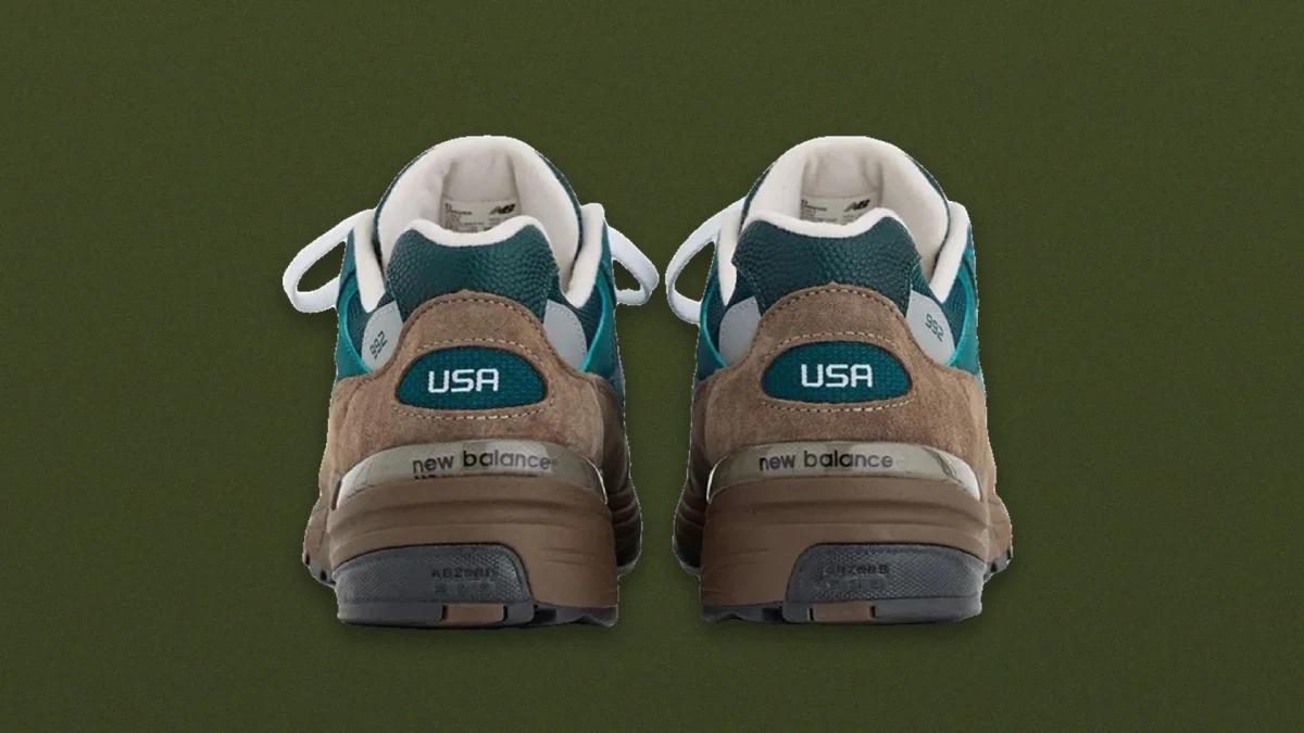 Rear view of teal, brown, and grey New Balance 992 sneakers with USA text on the heels.