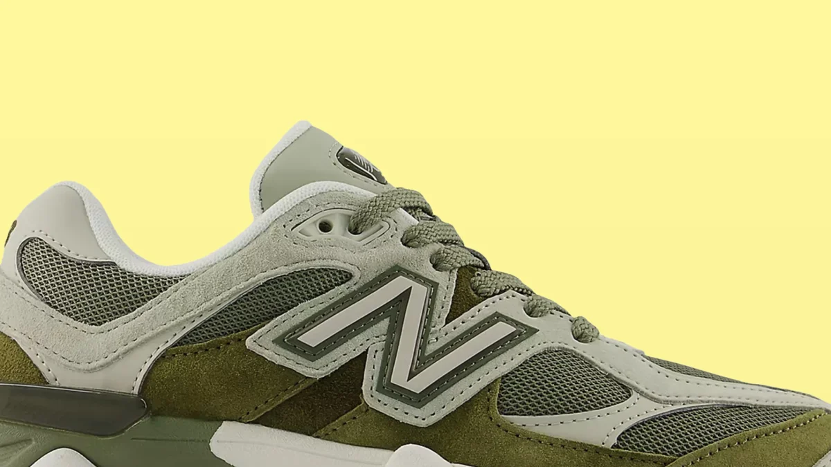 Green and gray New Balance sneaker with mesh and suede panels on a yellow background.