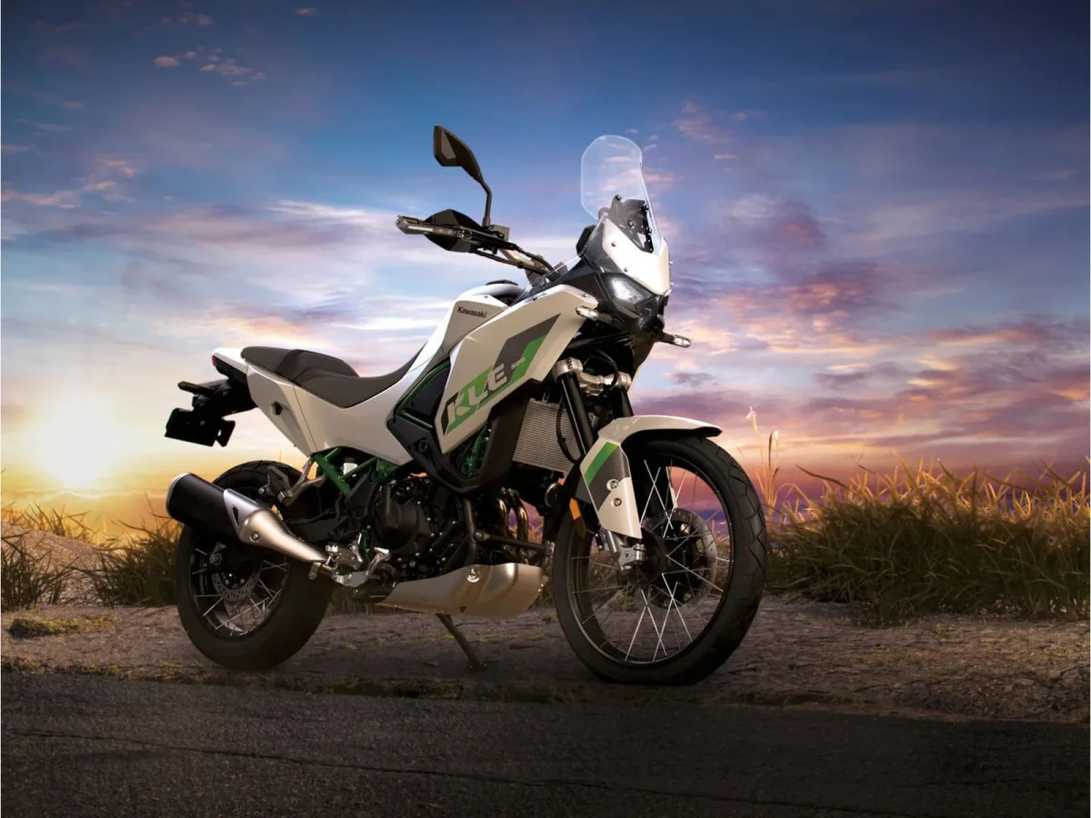 White and green Kawasaki KLE 500 adventure motorcycle parked on a dirt path at sunset.