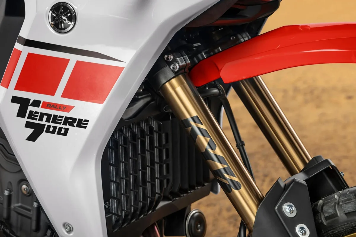 White Yamaha Tenere 700 Rally motorcycle in a close-up view, featuring red graphics, a black radiator, and gold-colored front fork tubes.