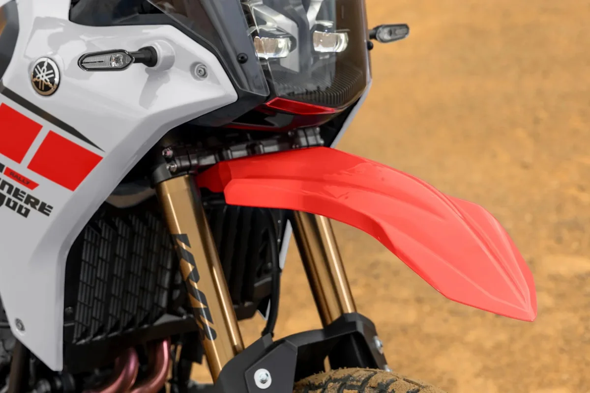 Close-up of a white Yamaha Ténéré 700 Rally motorcycle with a high-mounted red front fender, gold-colored front forks, and LED headlights.