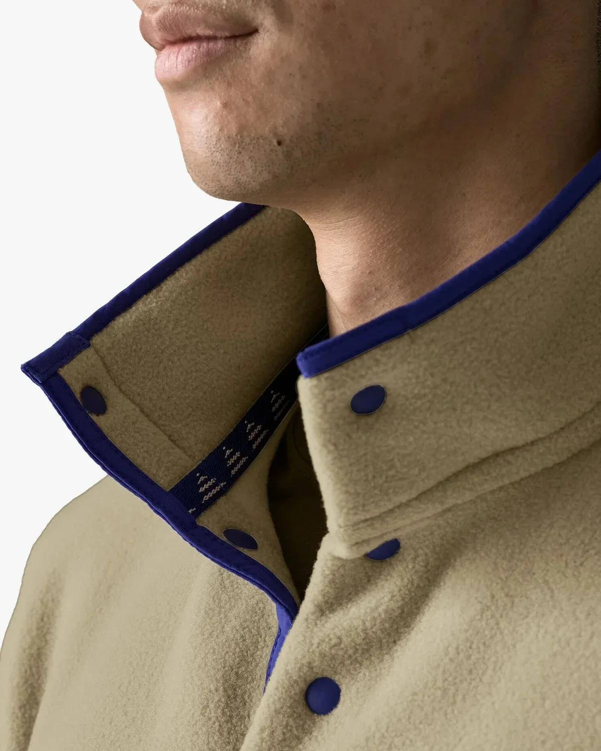 Tan fleece pullover with a stand-up collar, deep blue binding, and matching snap-button closure.