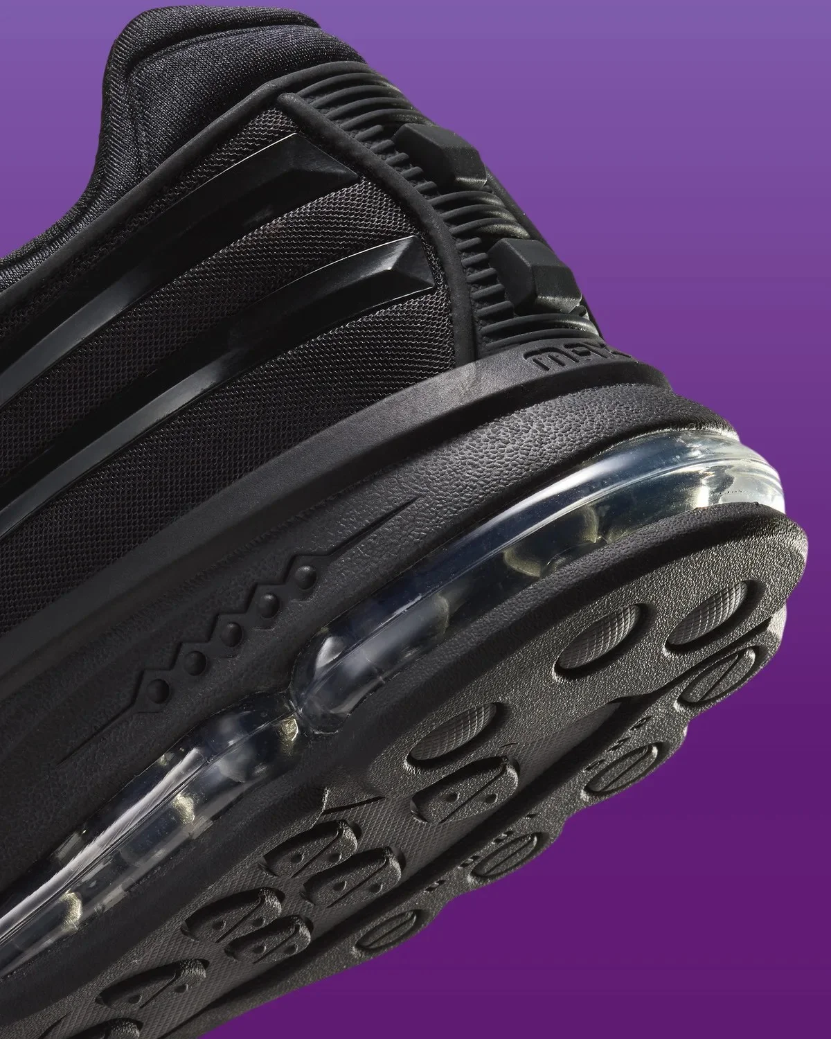 Close-up of a black athletic shoe, highlighting the textured sole and clear air-cushioning unit, set against a purple background.