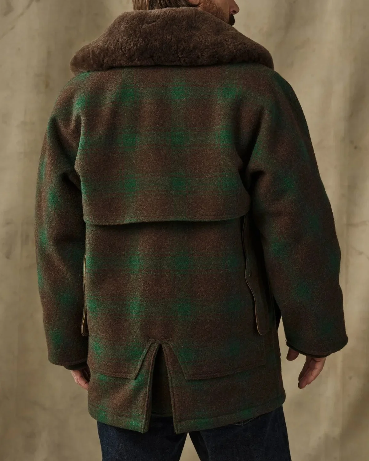 Brown and green plaid wool jacket featuring a brown faux-fur collar and a back storm flap.