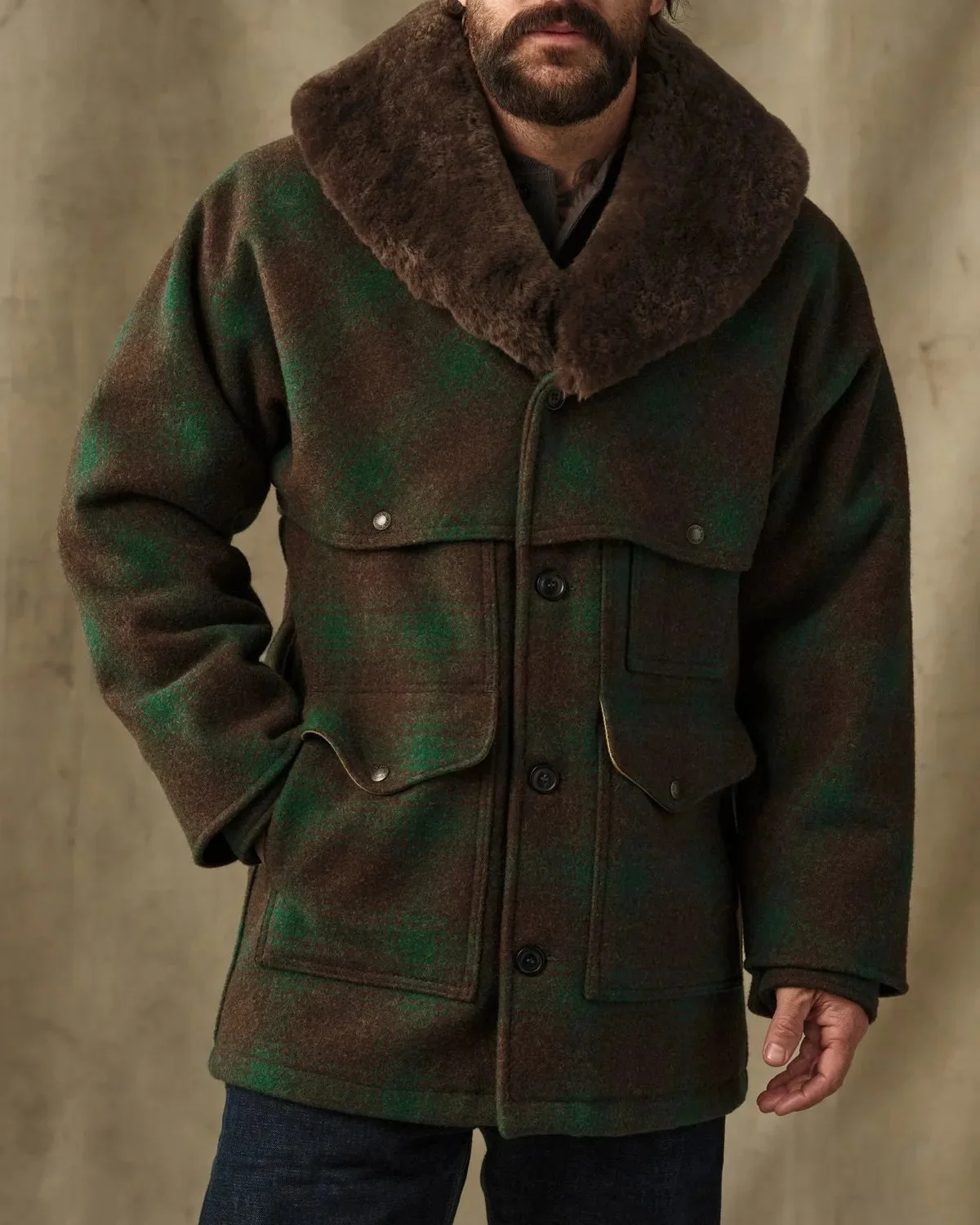 Green and brown plaid wool coat featuring a large fur collar, front button closure, and utility pockets.