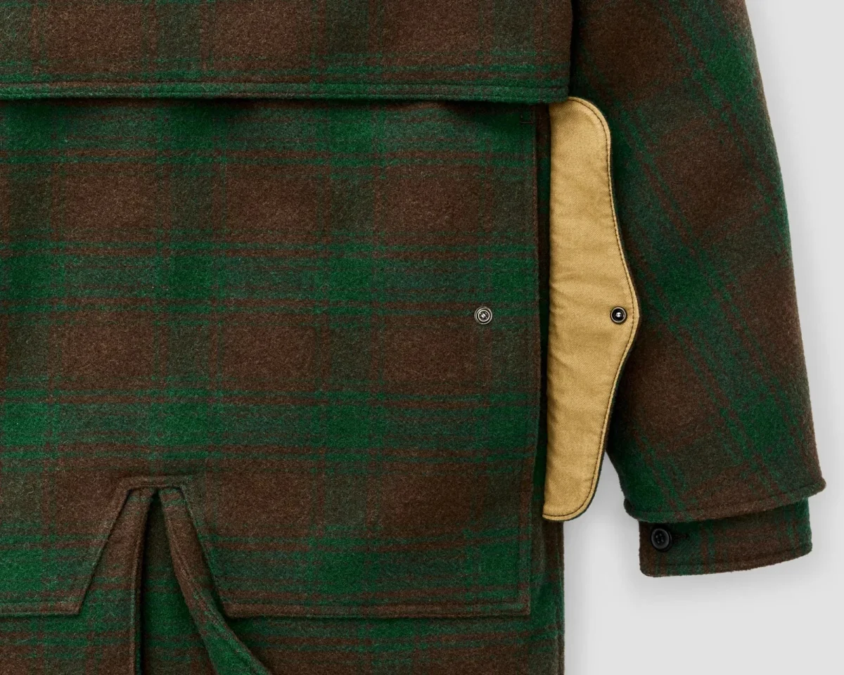 Close-up of a brown and green plaid wool-blend jacket featuring a tan pocket flap with a snap button closure.