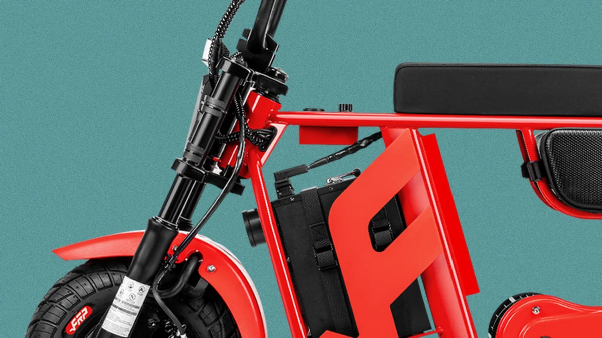 Red electric bike frame featuring a black battery pack, a flat seat, and knobby tires.