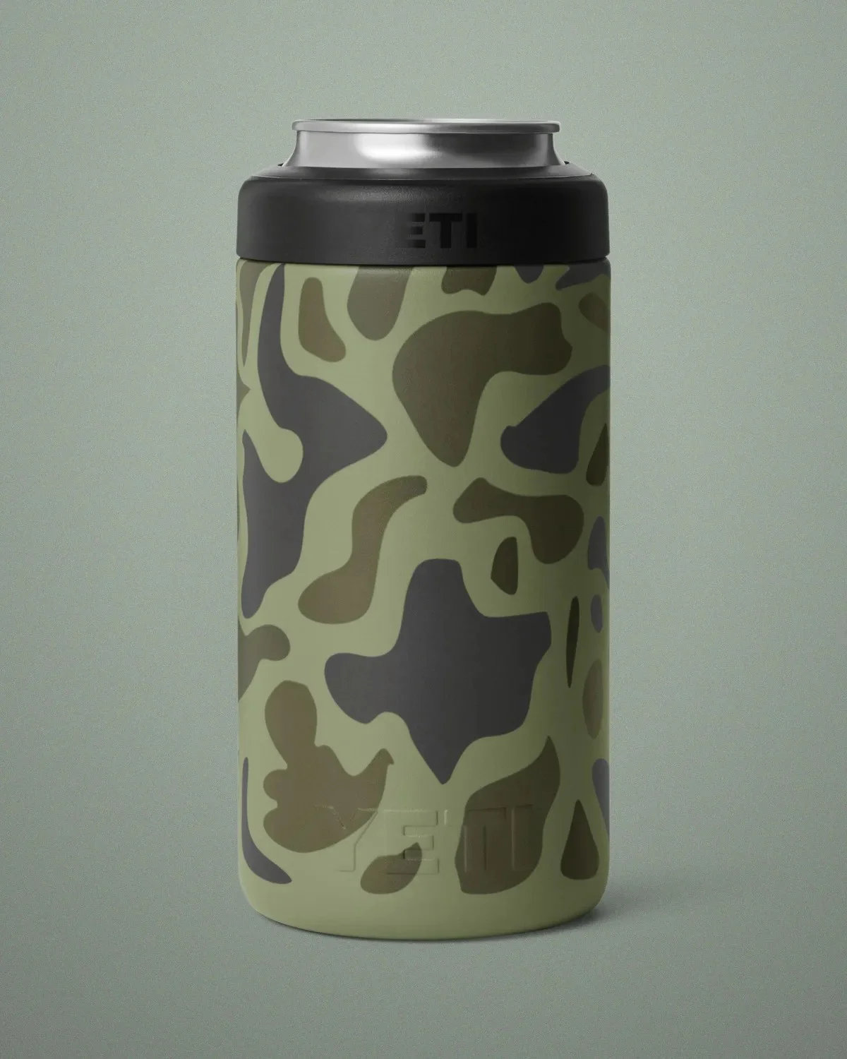 YETI stainless steel can insulator in a green and grey camouflage pattern with a black rim.