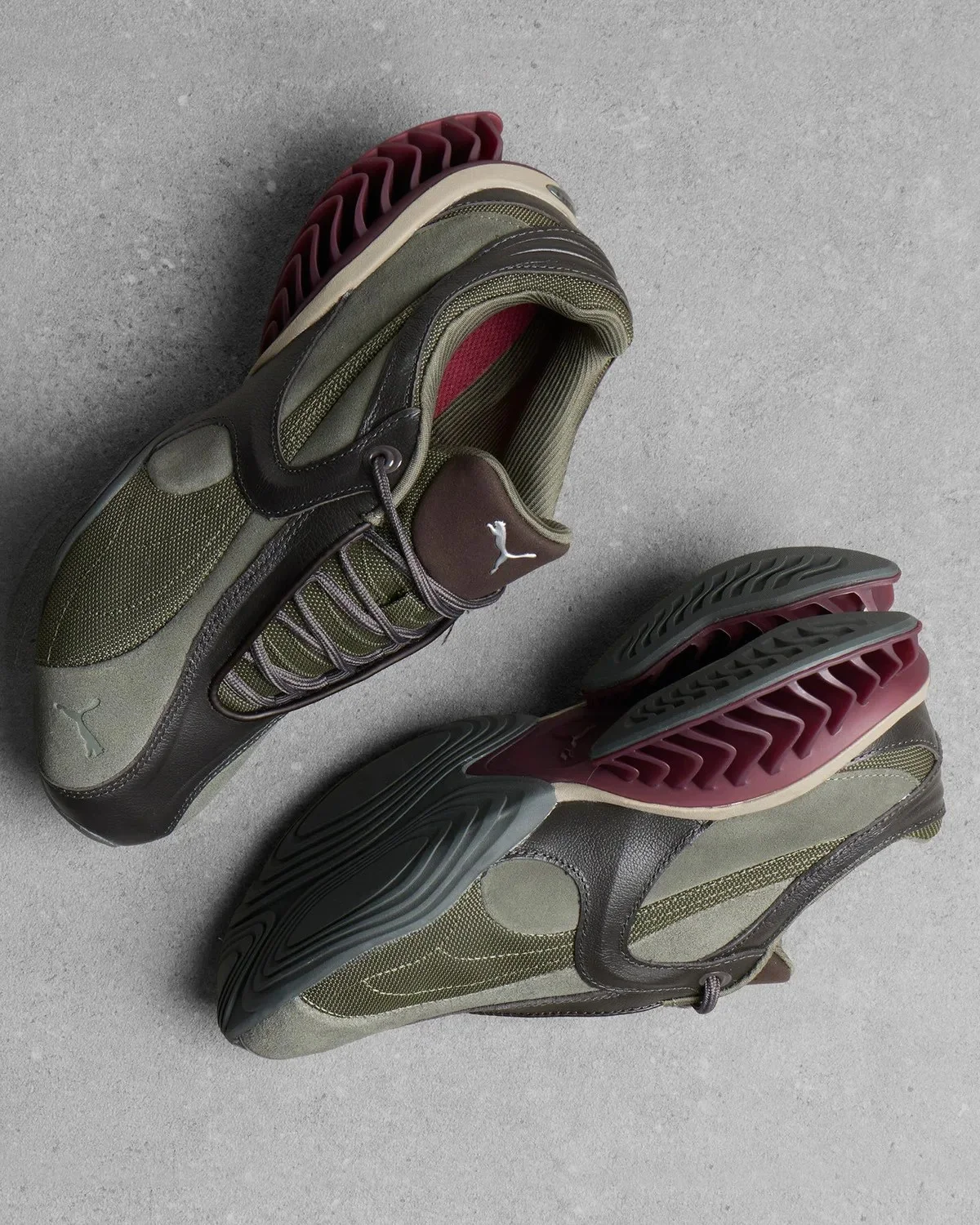 Pair of olive and dark brown Puma sneakers featuring a sculpted sole with maroon accents.