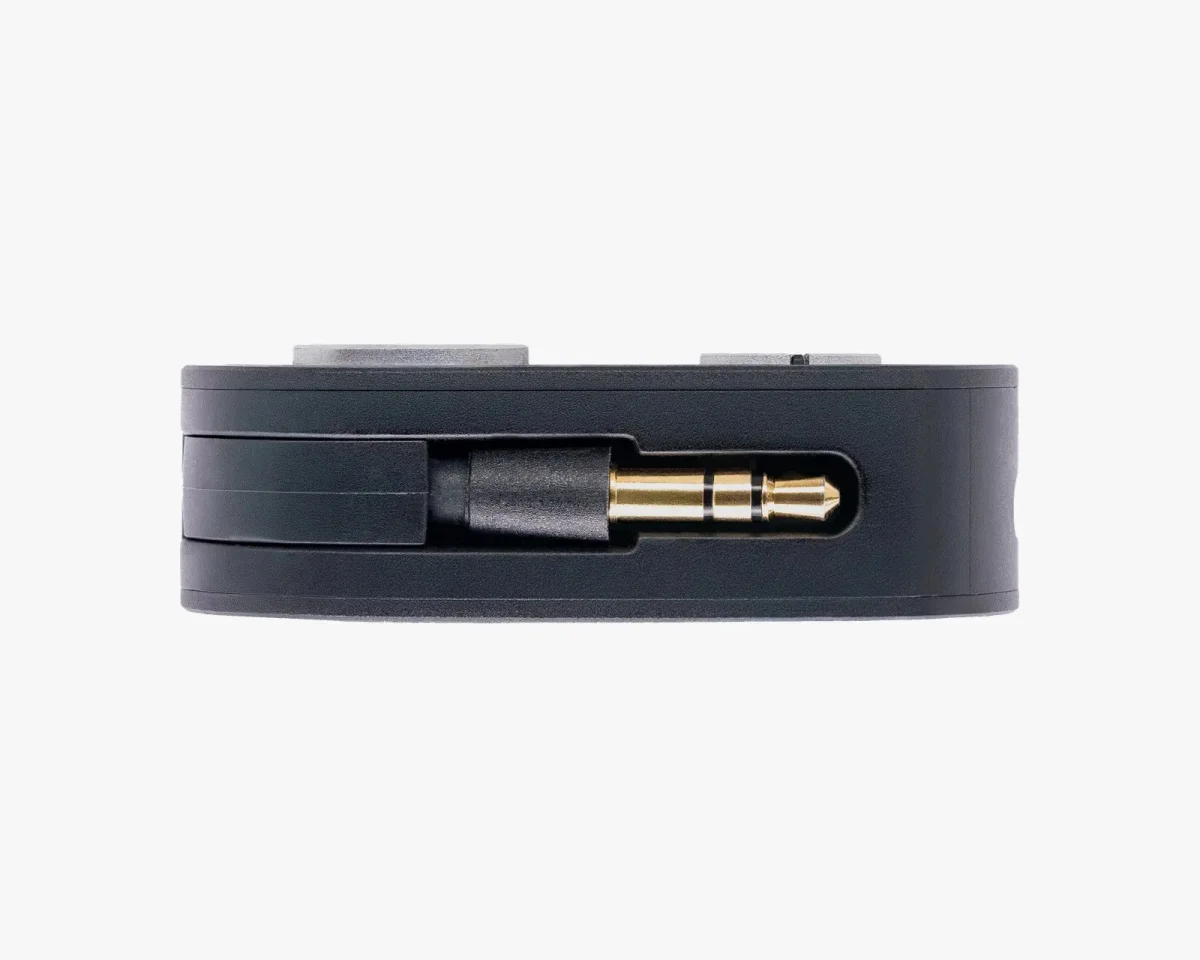 Black circular audio adapter featuring a recessed gold 3.5mm headphone jack on its side.