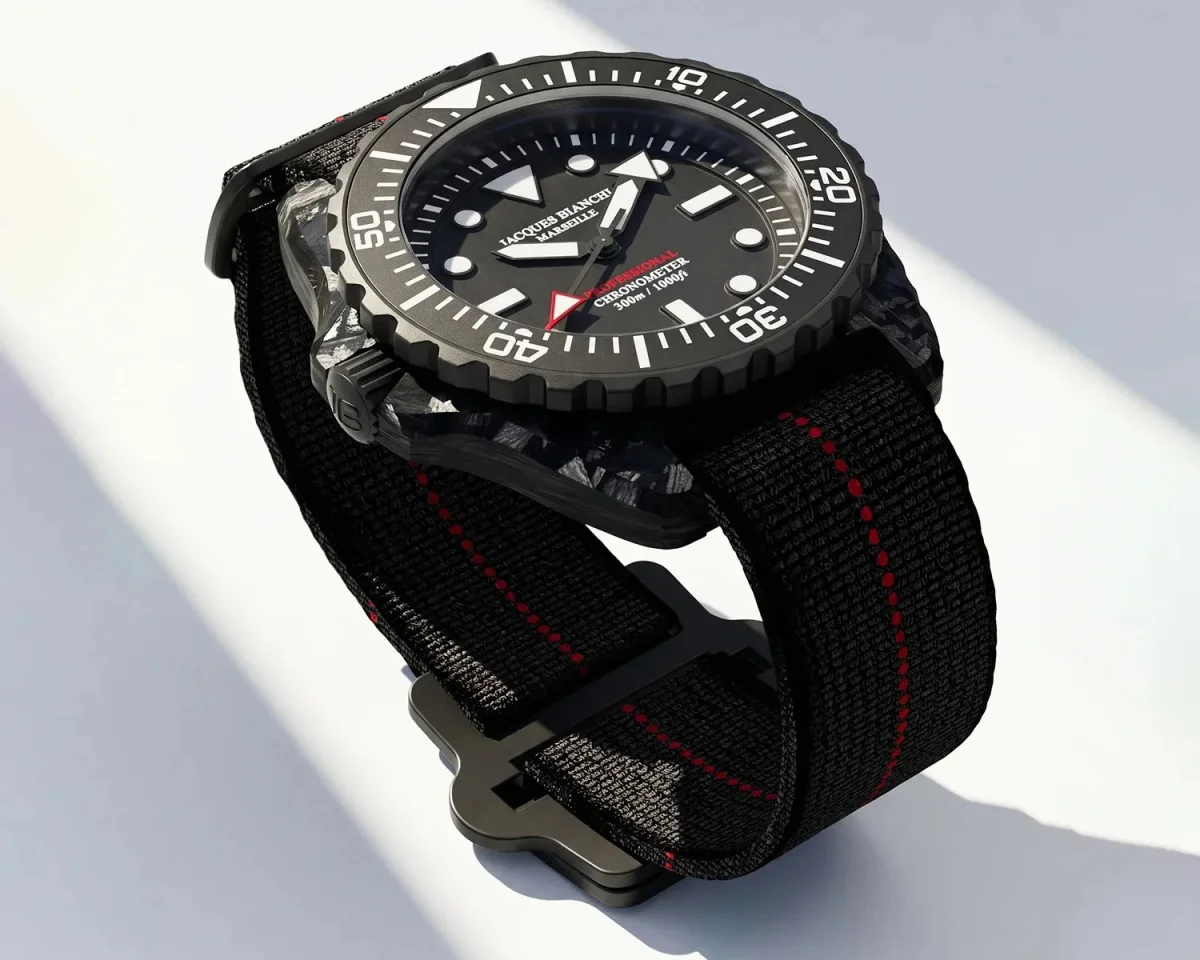 Black dive watch with a textured fabric strap and red stitching, shown on a light background.