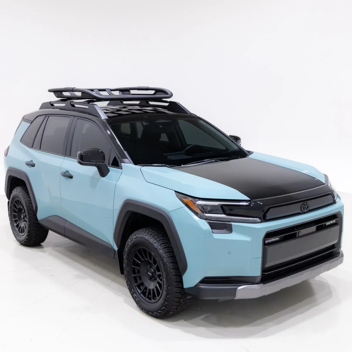 Light blue Toyota Land Cruiser featuring a black hood, roof rack, and black off-road wheels.