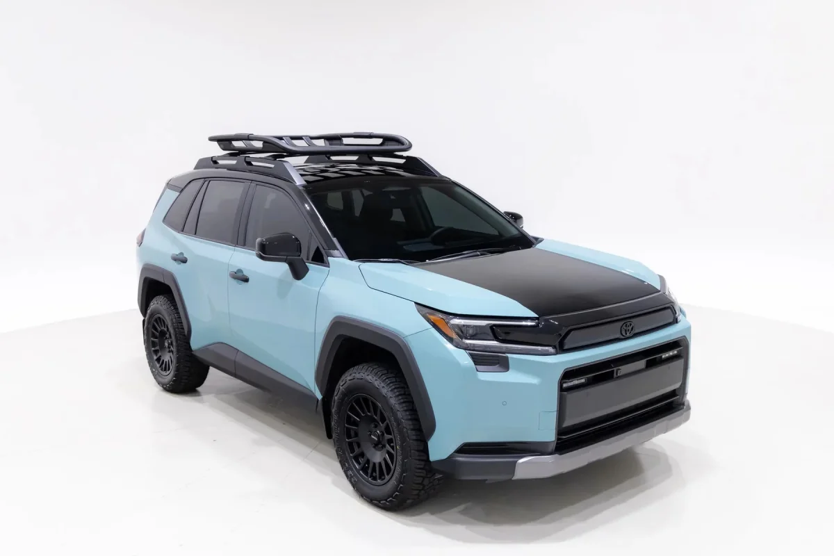Light blue and black Toyota SUV with a roof rack and off-road tires, viewed from the side against a white background.