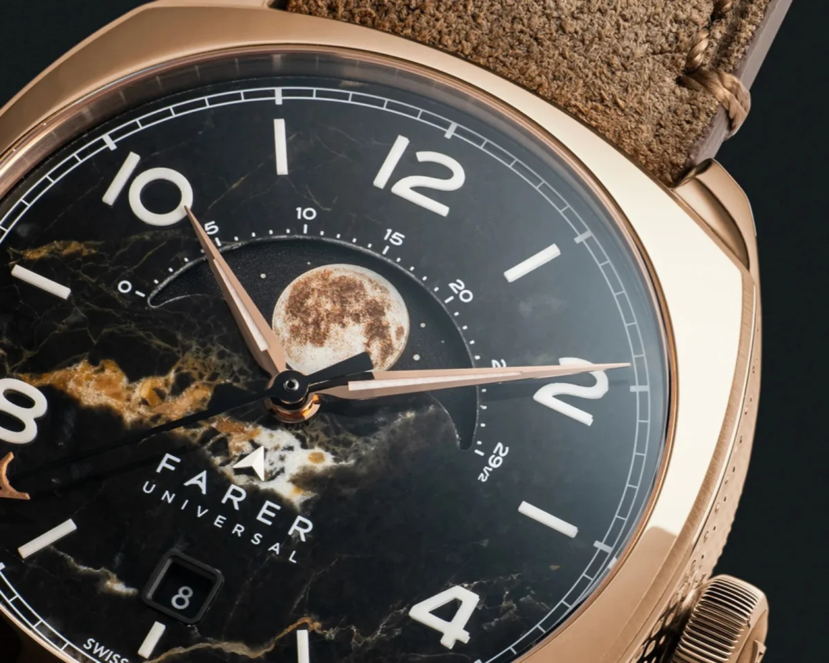 Farer Universal watch featuring a gold-tone case, a brown leather strap, and a black marble-patterned dial with a moon phase display.