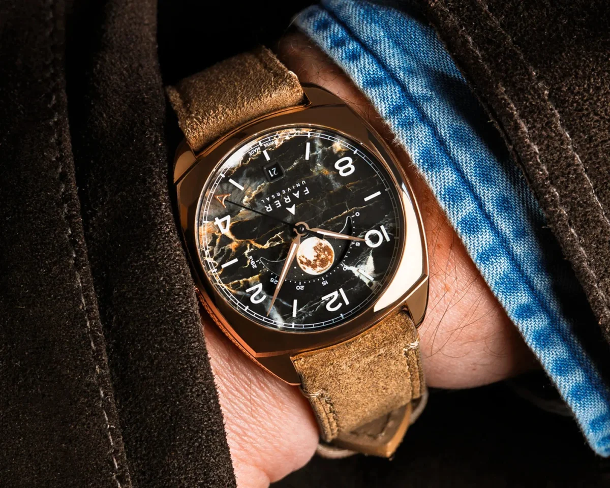 Farer Universal wristwatch with a cushion-shaped rose gold case, dark marbled dial, and moon phase display on a tan suede strap.