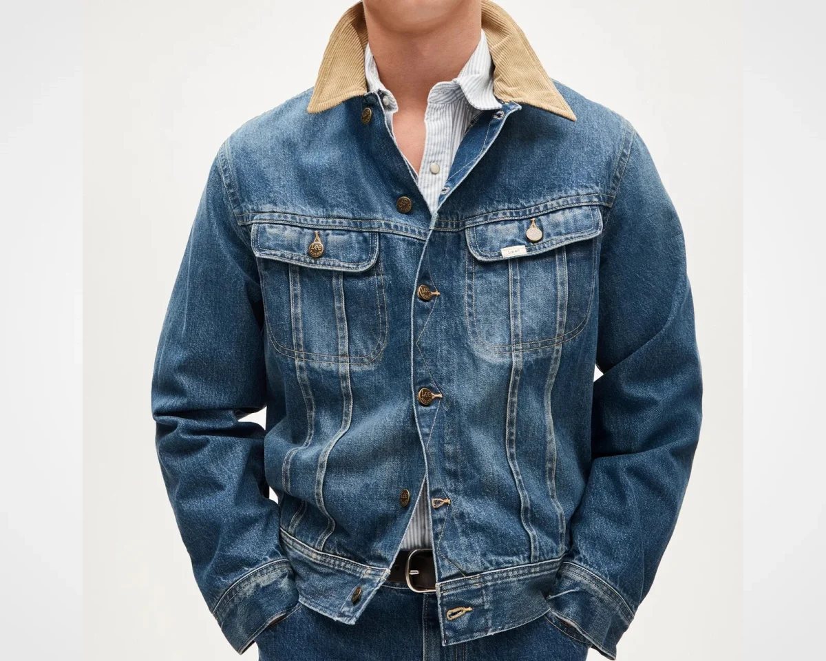 Blue denim jacket with two chest pockets and a tan corduroy collar, layered over a striped button-down shirt.