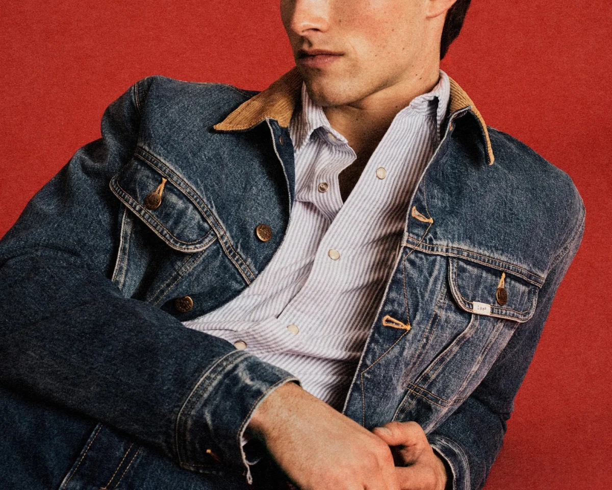Blue denim jacket with a brown corduroy collar layered over a light blue and white striped button-down shirt.