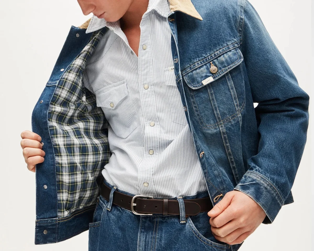 Blue denim jacket with a tan collar and plaid lining, layered over a striped button-down shirt.
