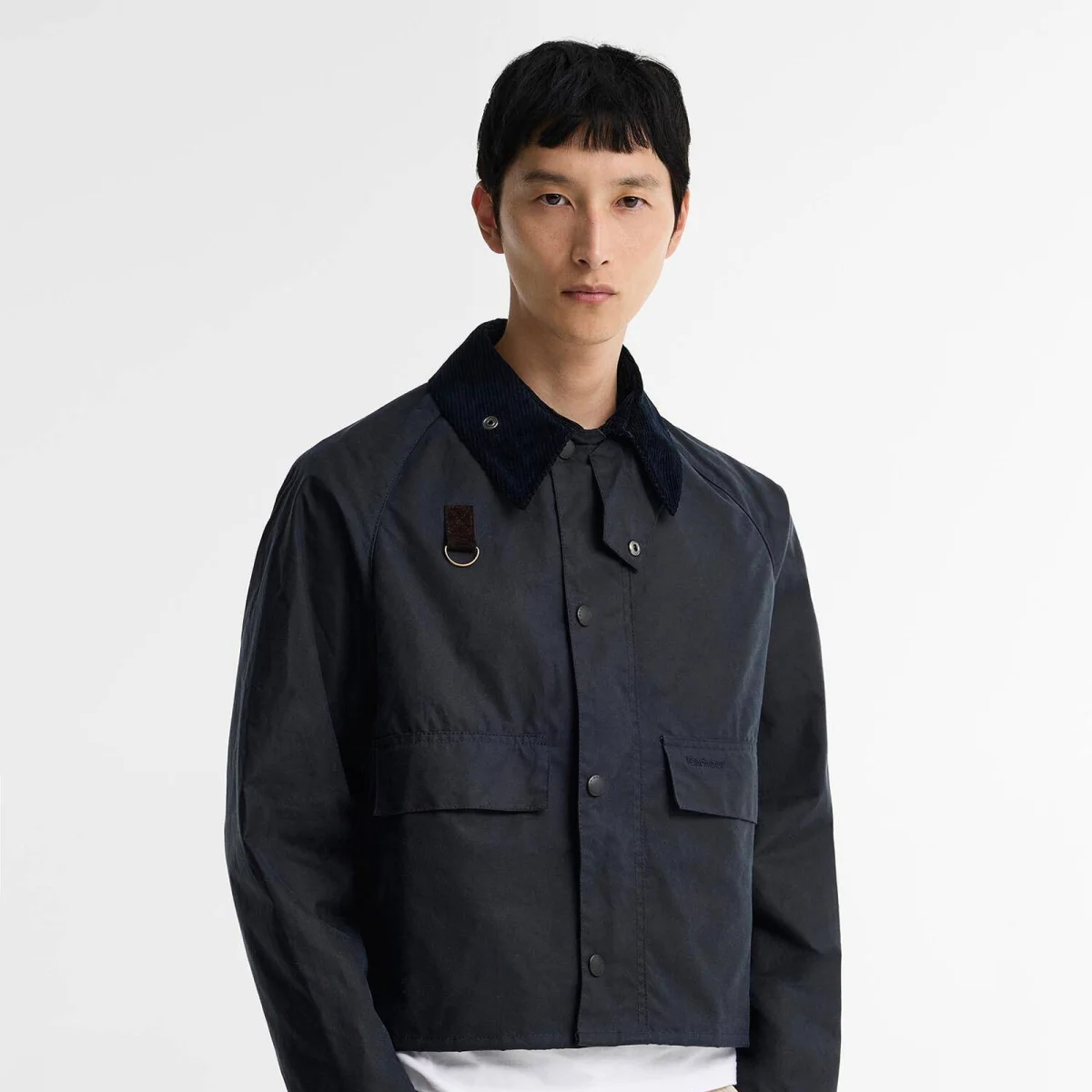 Navy blue cropped waxed jacket featuring a corduroy collar, front flap pockets, and a D-ring detail on the chest.