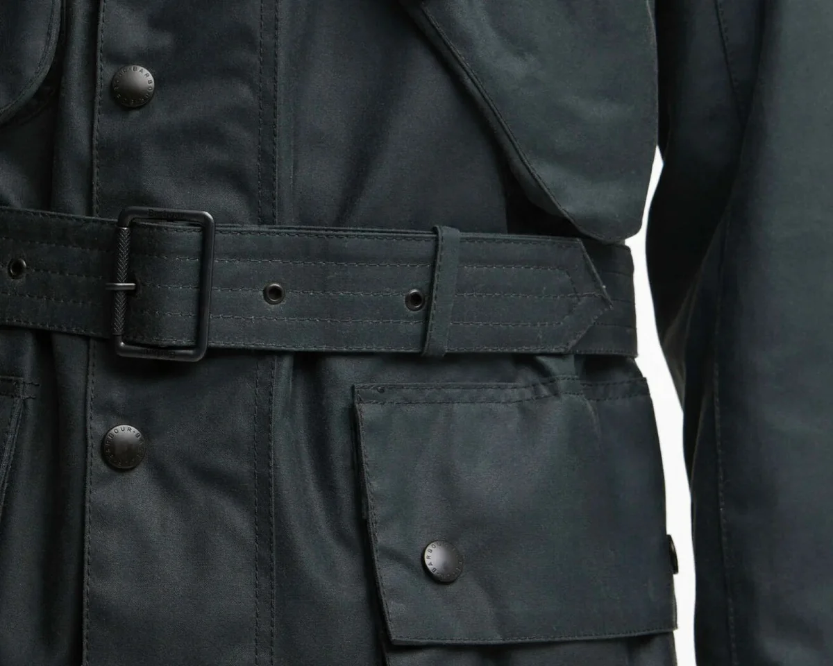 Dark green Barbour belted jacket featuring a buckled waist, a front pocket with a snap button, and branded hardware.