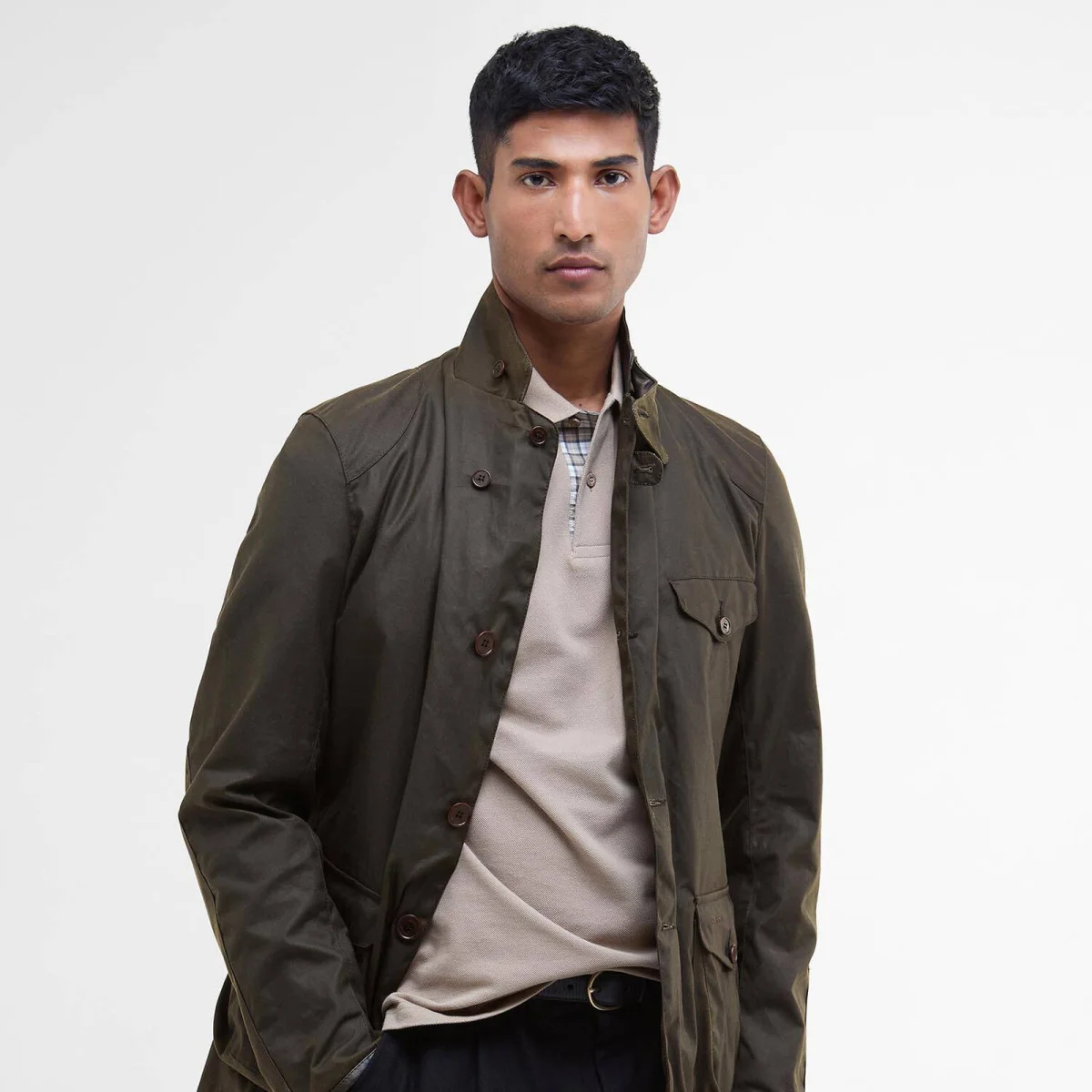 Olive green wax jacket worn over a light brown collared shirt.