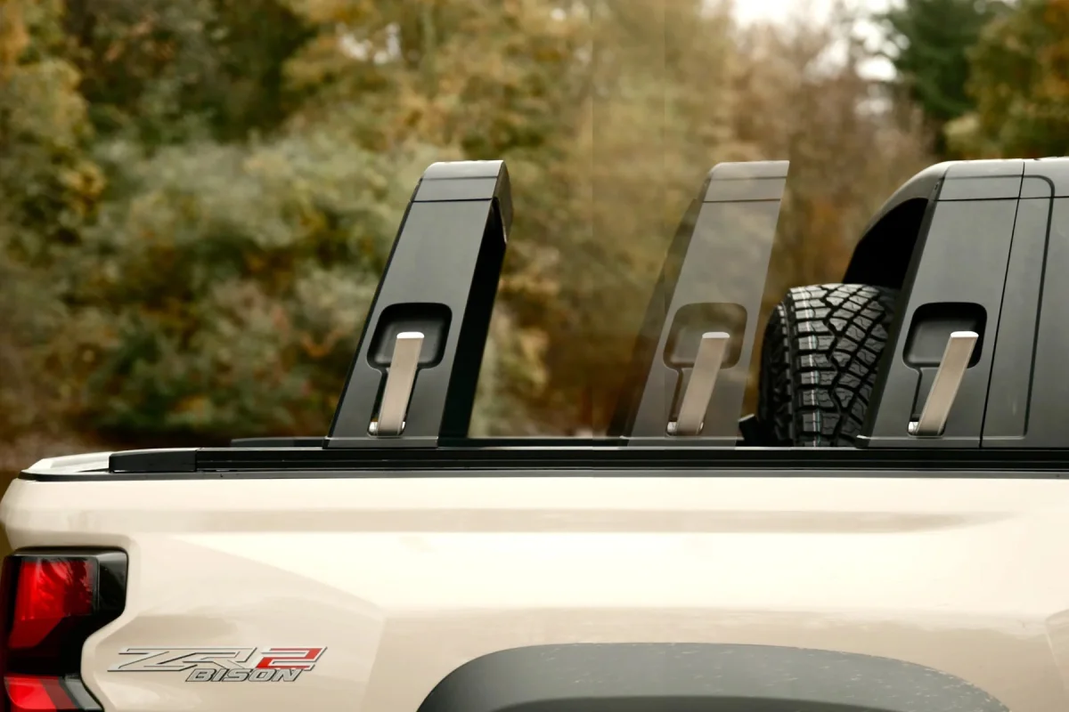 Tan pickup truck rear bed featuring black sport bars, a spare tire mounted behind the cab, and a ZR2 Bison badge on the quarter panel.