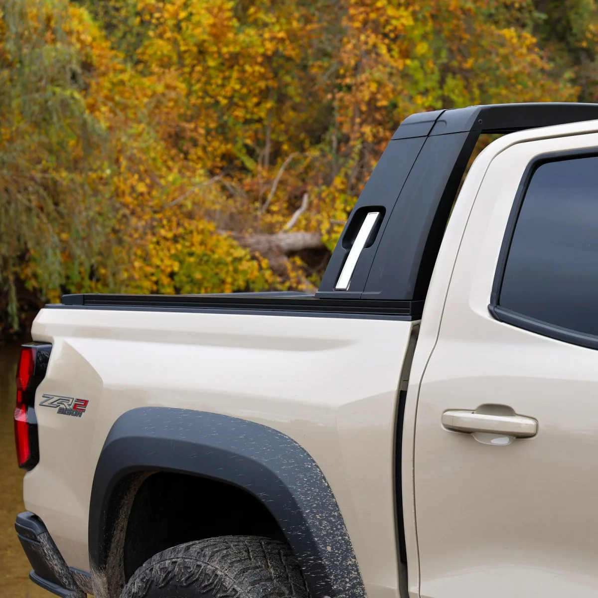 Side view of a tan pickup truck bed featuring a black sport bar, ZR2 Bison badging, and black fender flares.