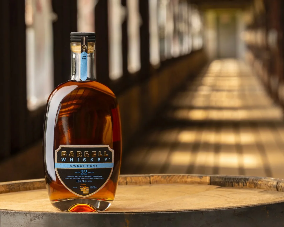 Bottle of Barrell Whiskey Sweet Peat aged 22 years, resting on a wooden barrel.