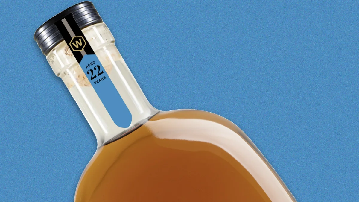 Close-up of a liquor bottle neck with a label reading Aged 22 Years and a W logo, set against a blue background.