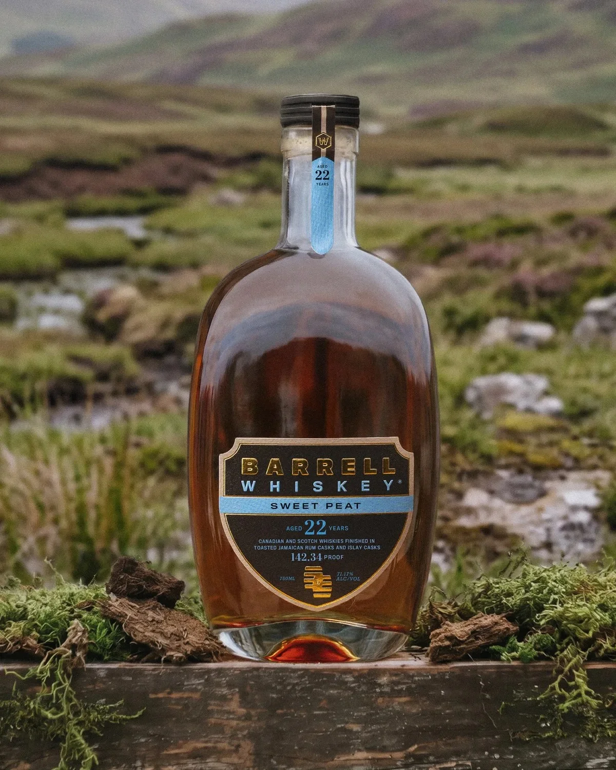 Barrell Whiskey Sweet Peat bottle, aged 22 years at 142.34 proof, resting on a mossy wooden surface in a field.