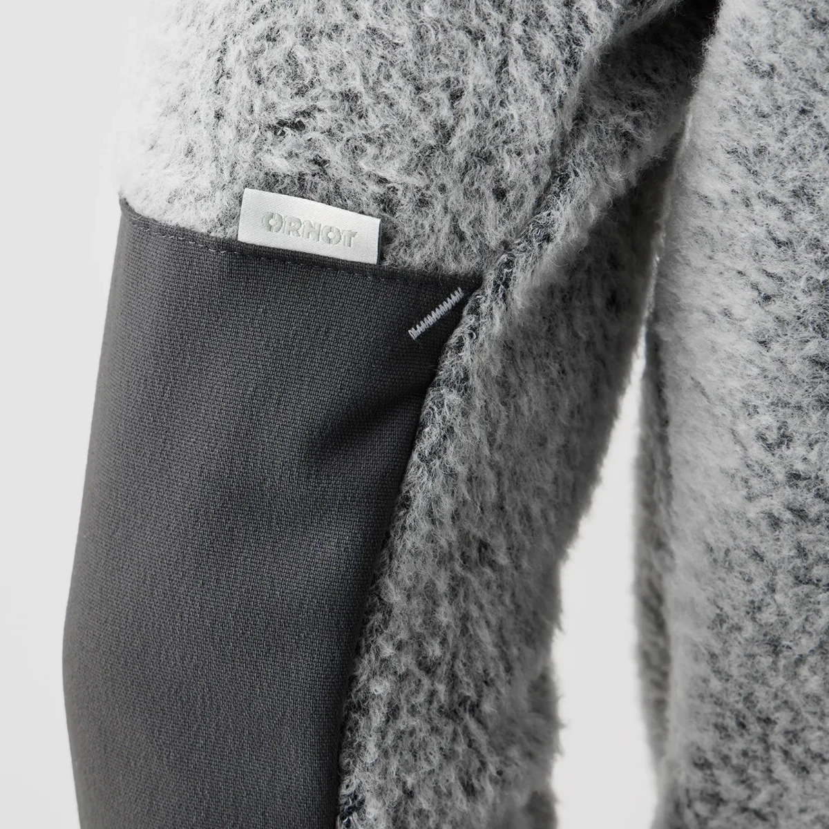 Close-up of a grey textured fleece sleeve featuring a dark grey elbow patch and a small white ORNOT brand label.