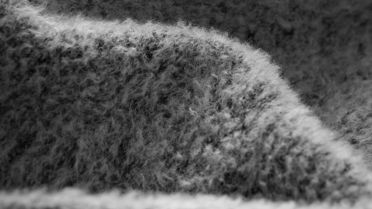Soft grey textured fabric with a fuzzy, curled pile in a close-up view.