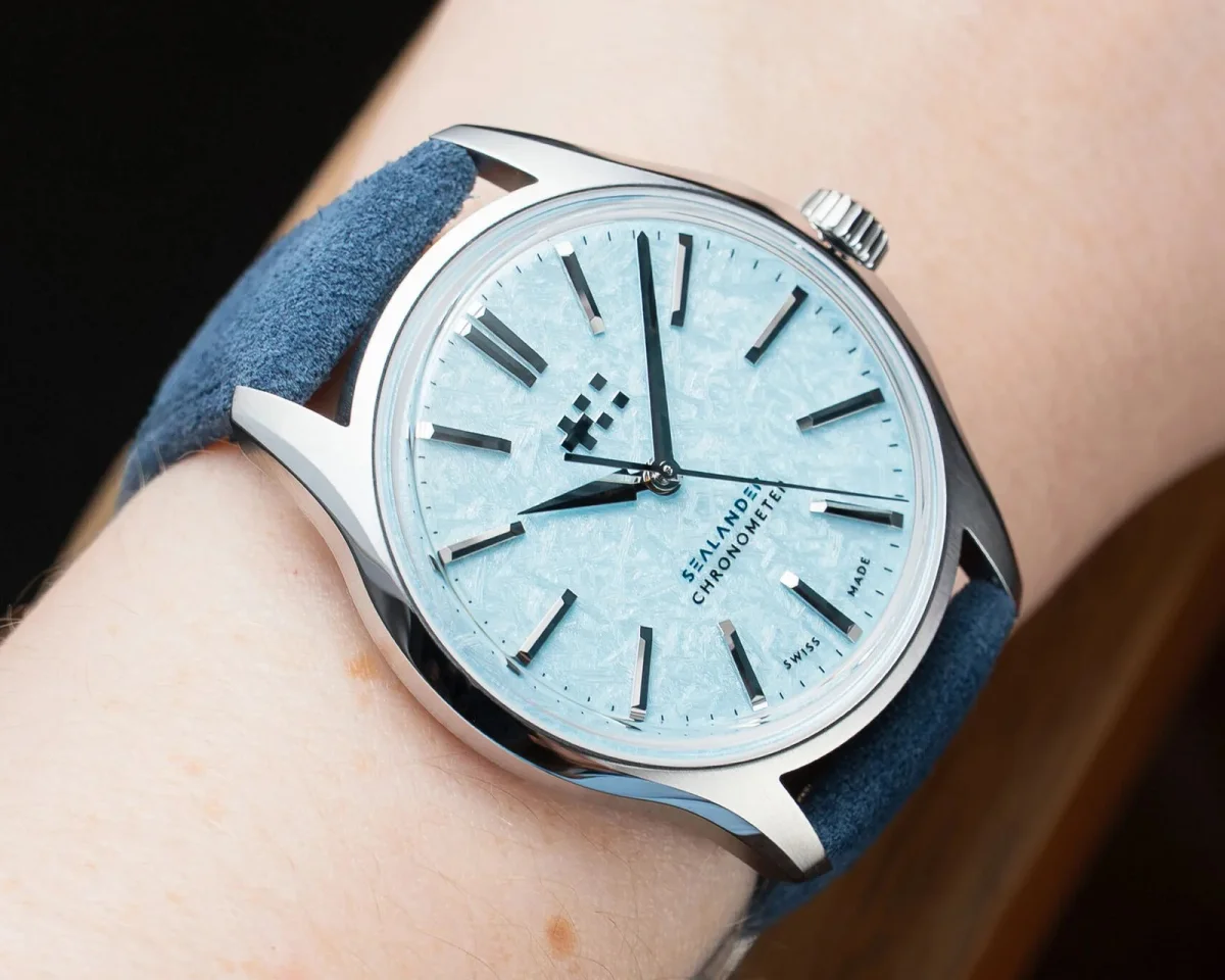 Christopher Ward Sealander chronometer watch with a textured light blue dial and blue suede strap on a wrist.