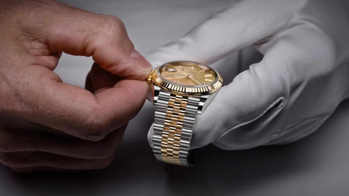 Two-tone gold and silver Rolex watch featuring a fluted bezel and jubilee bracelet, held in a gloved hand.