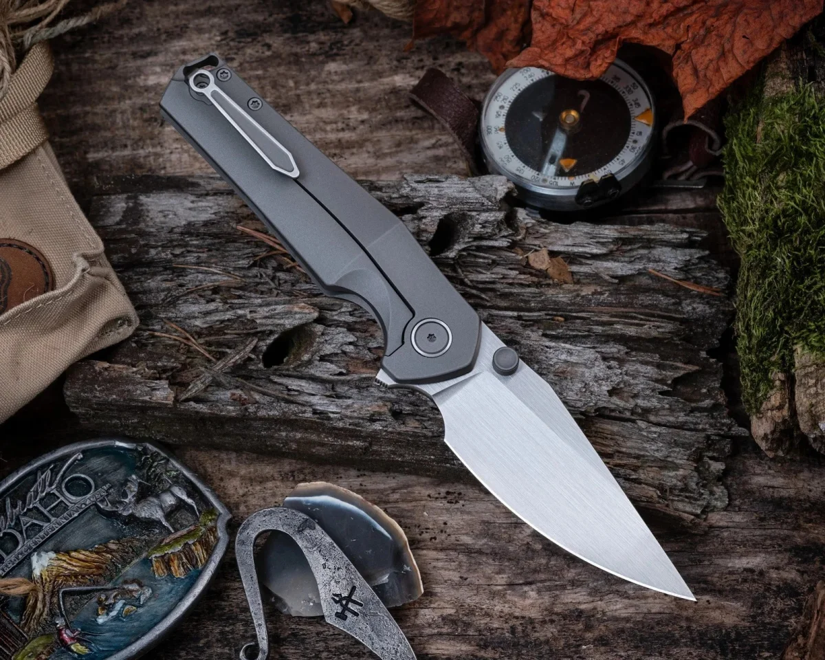 Gray folding pocket knife with a metal clip and drop-point blade, resting on weathered wood.