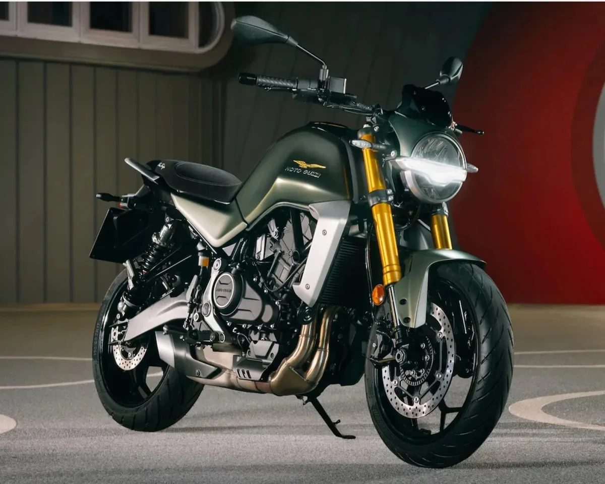 Matte olive green Moto Guzzi motorcycle featuring gold front forks and a round LED headlight.
