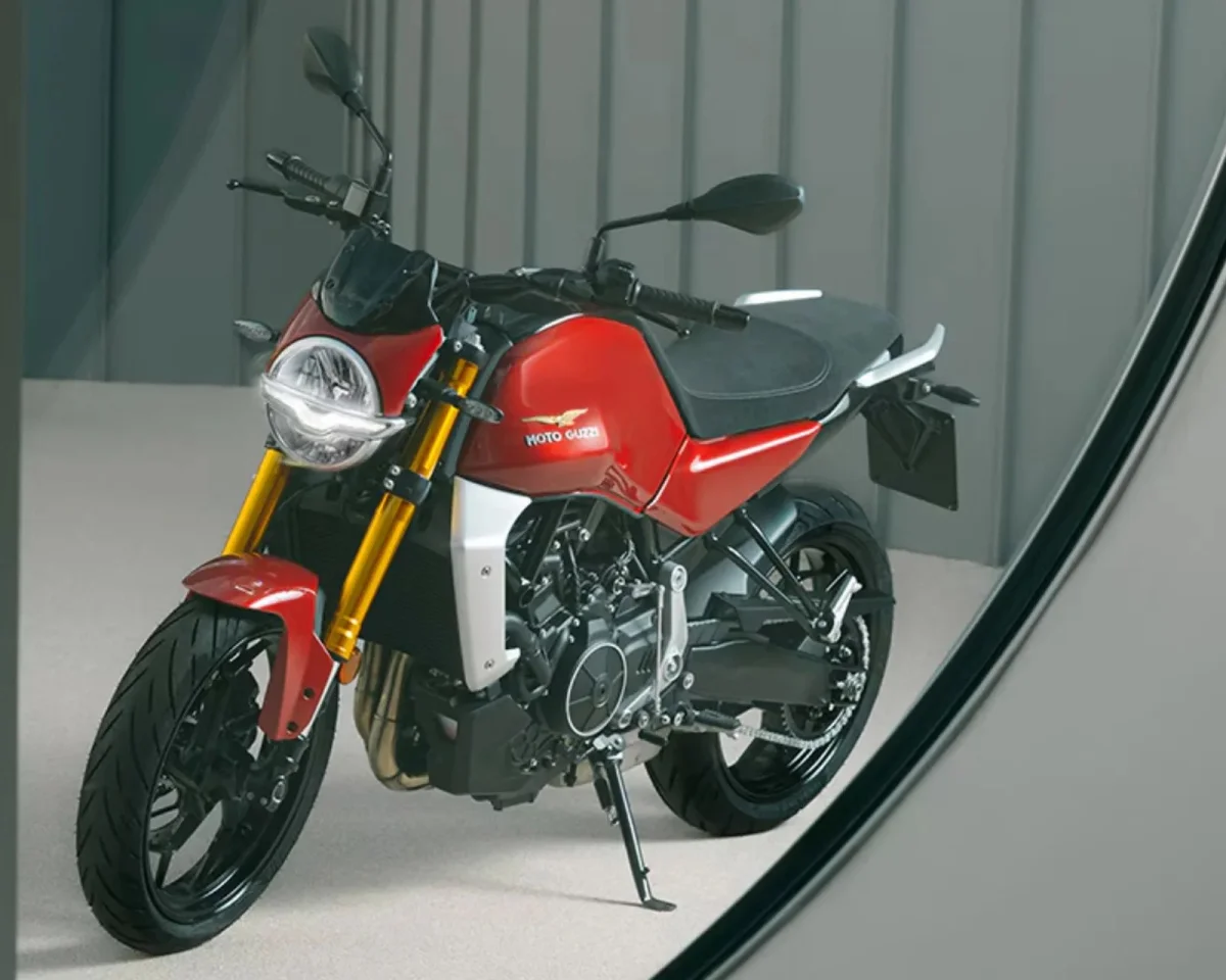 Red Moto Guzzi motorcycle featuring gold front forks and a black seat, parked on a light surface.