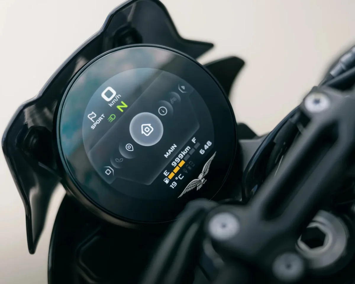 Circular digital motorcycle instrument cluster displaying a speed of 0 km/h, neutral gear, and menu icons.